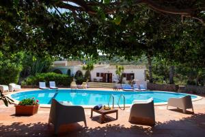 a swimming pool with chairs and a table and a house at Relais Le Nereidi in San Vito lo Capo