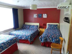 2 Betten in einem Zimmer mit roten Wänden in der Unterkunft Lynn Hill Guest House in East Dereham