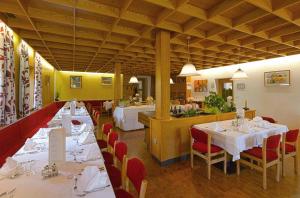 a dining room with tables and red chairs and a restaurant at Hotel Rose in Villabassa