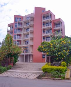 un immeuble d'appartements rose avec des fleurs devant lui dans l'établissement Beausejour Hotel, à Kigali