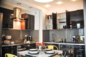 a kitchen with black cabinets and a table with chairs at 3D Szlak 77 Apartament in Kraków