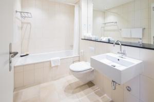 a bathroom with a sink and a toilet and a bath tub at Hotel Schweizerhof Basel in Basel