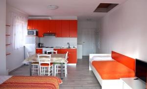 a kitchen with red cabinets and a table and chairs at Apartments Laura in Pinezici