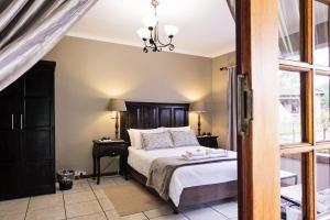 a bedroom with a bed and a chandelier at Holme Lea Manor in Piet Retief