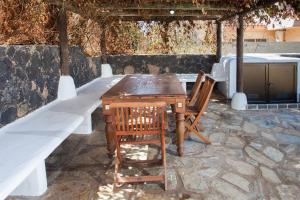 una mesa de madera y 2 sillas en un patio de piedra en Casa MINA en La Oliva