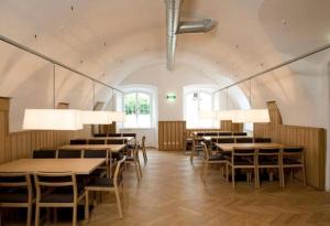 a dining room with tables and chairs and windows at Hotel Kolping Hallein in Hallein