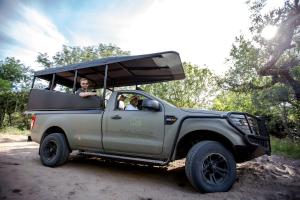 Un jeep gris con dos personas atrás. en Royal Thonga Safari Lodge en Sihangwane