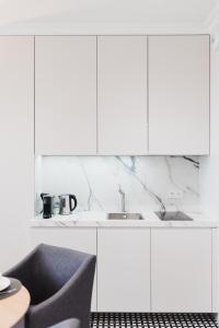 una cocina con armarios blancos y fregadero en LuxLux Apartments Metro Slodowiec, en Varsovia