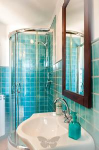 La salle de bains est pourvue de carrelage bleu, d'un lavabo et d'une douche. dans l'établissement B&B Mariposa, à Maratea