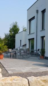 eine Terrasse mit Tischen und Stühlen vor einem Gebäude in der Unterkunft Hotel Apartment am Arbach in Eningen unter Achalm