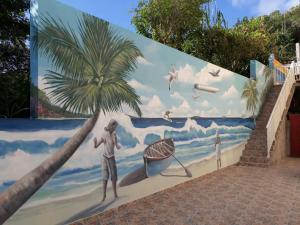 un mural de un hombre parado en la playa con una palmera en Residence fruit de la passion F4, en Sainte-Anne