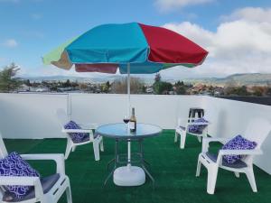 a table and chairs with a colorful umbrella on a roof at The Heart of Rotorua in Rotorua
