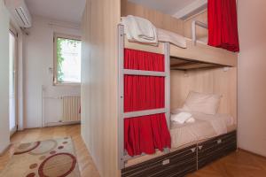 スコピエにあるUrban Hostel & Apartmentsのベッドルーム1室(赤いカーテン付きの二段ベッド1組付)