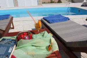 uma mesa com uma tigela de fruta ao lado de uma piscina em Villa Mila em Murter