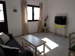 sala de estar con sofá, mesa y TV en Apartamento Malvasía Vv, en Arrecife