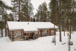 Cabaña de madera con nieve en el techo del bosque en Pikku-Junga, en Kuusamo