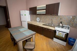 a kitchen with a stove and a sink and a table at Guesthouse Hillside in Tbilisi City