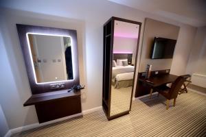 a bathroom with a mirror and a television at Bannatyne Hotel Durham in Durham