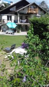 een huis met een tuin met stoelen en een parasol bij La Grande Lauze in Champcella