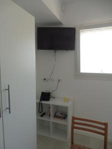 Habitación con TV en la pared y silla en Maiolica guest house,a delicious studio, en Siracusa