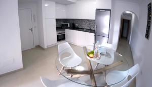 プエルト・デ・ラ・クルスにあるIriarte Serenity with FREE PARKINGのキッチン(ガラステーブル、白い椅子2脚付)