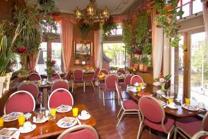 a dining room with tables and chairs and windows at Nadia Hotel in Amsterdam