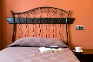 a bed with a book and a remote control on it at Casa Goas in Abadín