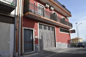 a red building with two doors and a balcony at Il Cuore dell'Etna in Belpasso