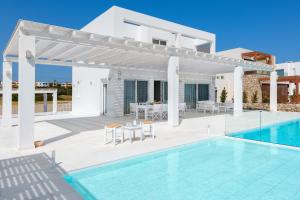 a white villa with a swimming pool and a patio at Maria & Nada Beachfront Villas in Kolymbia