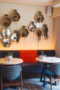 two tables in a restaurant with potted plants on the wall at The Corner London City in London