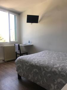 a bedroom with a bed and a desk and a television at L'ENTRE-POTS in Sartrouville