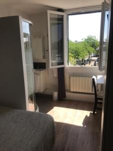 a bedroom with a bed and a large window at L'ENTRE-POTS in Sartrouville