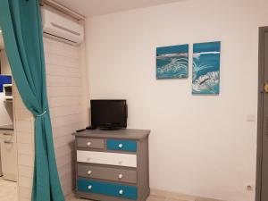 - une chambre avec une commode et une télévision dans l'établissement Les lecques Turquoise, à Saint-Cyr-sur-Mer