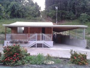 eine kleine Holzhütte mit einer großen Veranda in der Unterkunft La Belle Creole in Morne-à-lʼEau