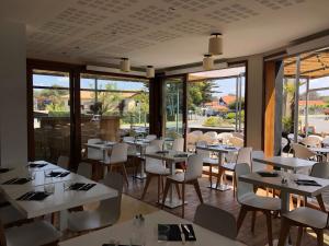 a restaurant with white tables and chairs and windows at Le Pavillon Bleu in Cap-Ferret