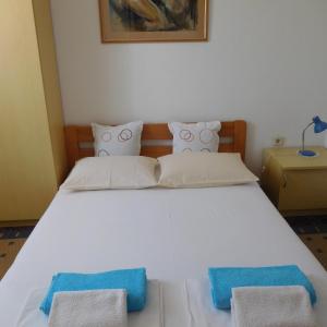 uma grande cama branca com duas toalhas azuis em Apartments Marija & Ivana, Malinska em Malinska