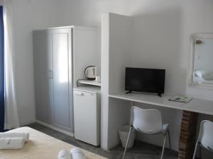 Cette chambre blanche dispose d'une télévision et d'un bureau avec des chaises. dans l'établissement Naoussa Hotel Paros by Booking Kottas, à Náoussa