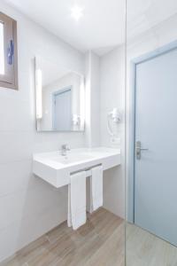 a white bathroom with a sink and a mirror at Apartamentos Lago in Colònia de Sant Jordi