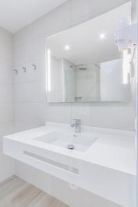 a white bathroom with a sink and a mirror at Apartamentos Lago in Colònia de Sant Jordi