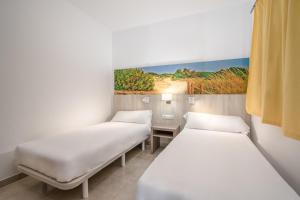 2 camas en una habitación con un cuadro en la pared en Apartamentos Lago, en Colonia de Sant Jordi