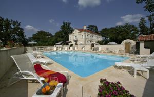 a swimming pool with white chairs and a building at Le Manoir Saint Jean in Saint-Paul-dʼEspis