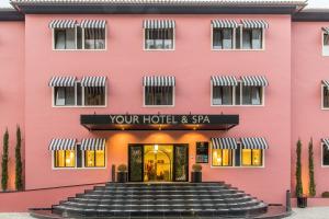 ein rosafarbenes Gebäude mit einer Treppe, die zu einem Hotel führt in der Unterkunft Your Hotel & Spa Alcobaça in Alcobaça