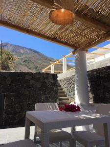 stół i krzesła na patio z kamienną ścianą w obiekcie Casa Martha w mieście Stromboli
