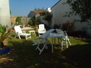 three chairs and a table in a yard at L'oiseliere in Sainte-Marie-de-Ré