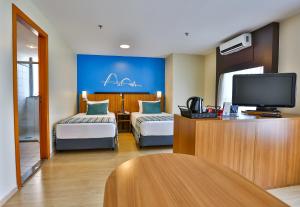 a hotel room with two beds and a flat screen tv at Comfort Hotel Taguatinga in Taguatinga