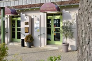 un magasin avec des portes vertes et des plantes en pot devant dans l'établissement Logis Auberge des Vieux Chenes, à Malemort-sur-Corrèze