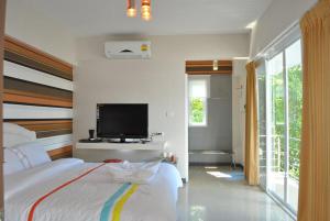 um quarto com uma cama e uma televisão de ecrã plano em O.U.M. Hotel - โรงแรมโอยูเอ็ม em Uttaradit