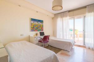 a bedroom with two beds and a desk with a laptop at Villa Jarama in Málaga