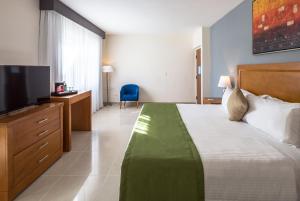 um quarto de hotel com uma cama e uma televisão em Wyndham Garden Playa del Carmen em Playa del Carmen