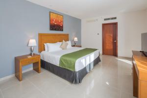 a bedroom with a large bed and a television at Wyndham Garden Playa del Carmen in Playa del Carmen